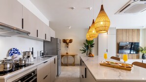 Une cuisine moderne dotée d’un îlot central, d’appareils électroménagers en acier inoxydable et d’un luminaire suspendu.