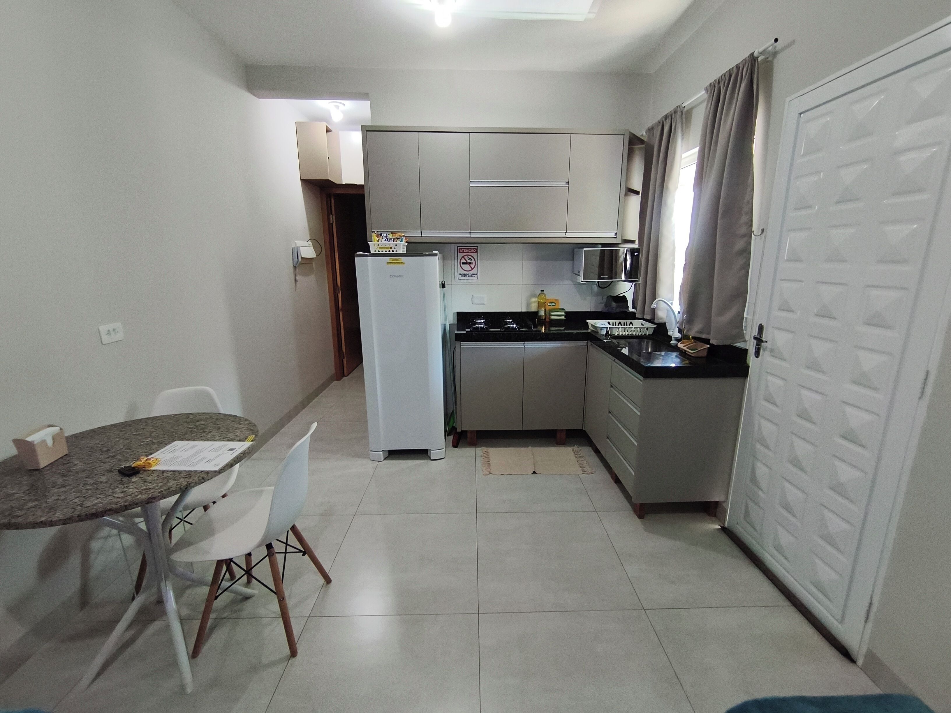 Una cocina compacta con refrigerador, microondas y lavamanos. Hay una mesa de comedor con sillas.