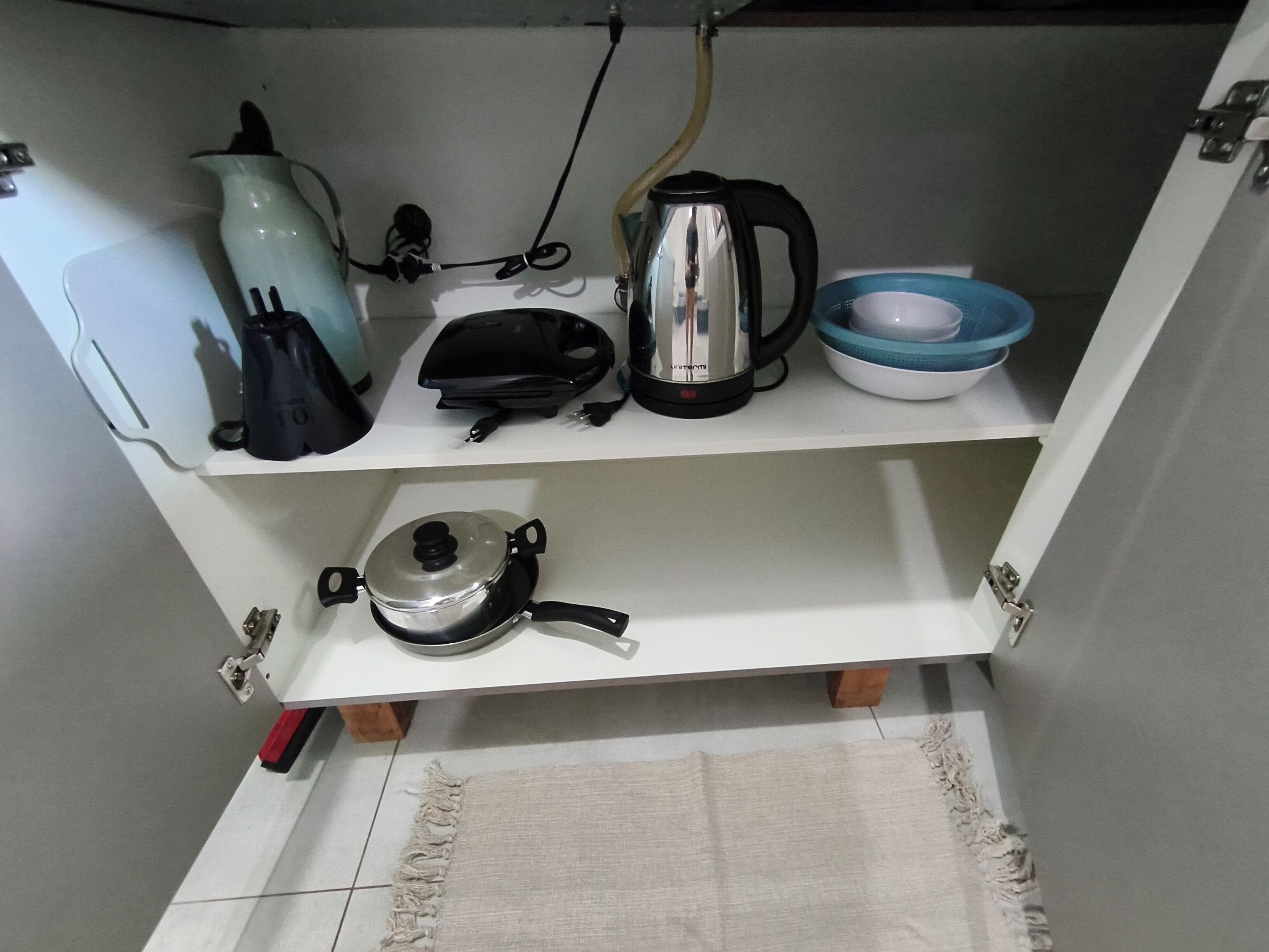 Una cuina amb una paperera, una cafetera, una olla i un bol damunt del taulell.