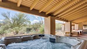 Ein Whirlpool unter einer Holzpergola mit Blick auf eine Wüstenlandschaft.