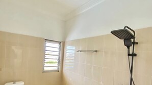 A bathroom with a toilet, a shower, and a window.