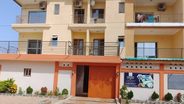 A multi-story hotel with a central entrance, balconies, and a landscaped courtyard.