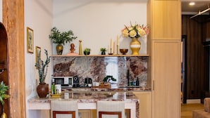 A modern kitchen with a marble countertop, wooden chairs, and a built-in oven.