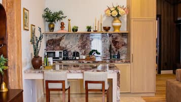 Une cuisine moderne avec un plan de travail en marbre, des chaises en bois et un four encastré.