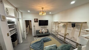 Una camera da letto moderna con un letto, una TV, un armadio e un corridoio che porta a un'altra stanza.
