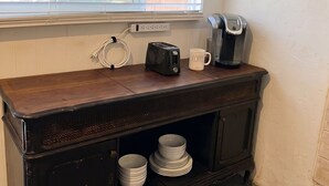 Een keuken met een houten aanrecht, een broodrooster, een koffiezetapparaat en een prikbord aan de muur.