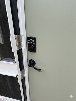 Uma porta com fechadura eletrônica, maçaneta e tela mosquiteira.