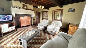 Una sala de estar con piso a cuadros, una chimenea, un televisor y muebles cubiertos.