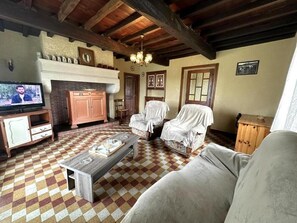 A living room with a checkered floor, a fireplace, a television, and covered furniture. - Galas - HAURIET - Vacation Rental (HAURIET)