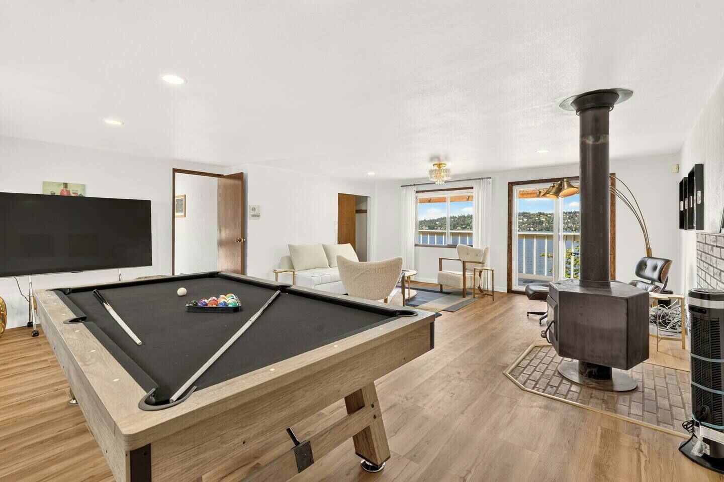 Una mesa de billar en una habitación con chimenea, un sofá y un televisor.