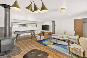 Ein modernes Wohnzimmer mit Kamin, Sofa, Couchtisch und Billardtisch.