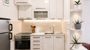 Une cuisine moderne avec des meubles blancs, un four encastré, un four à micro-ondes et un évier.