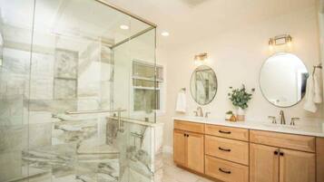 Une salle de bain avec une douche à parois de verre, des meubles en bois et deux miroirs.