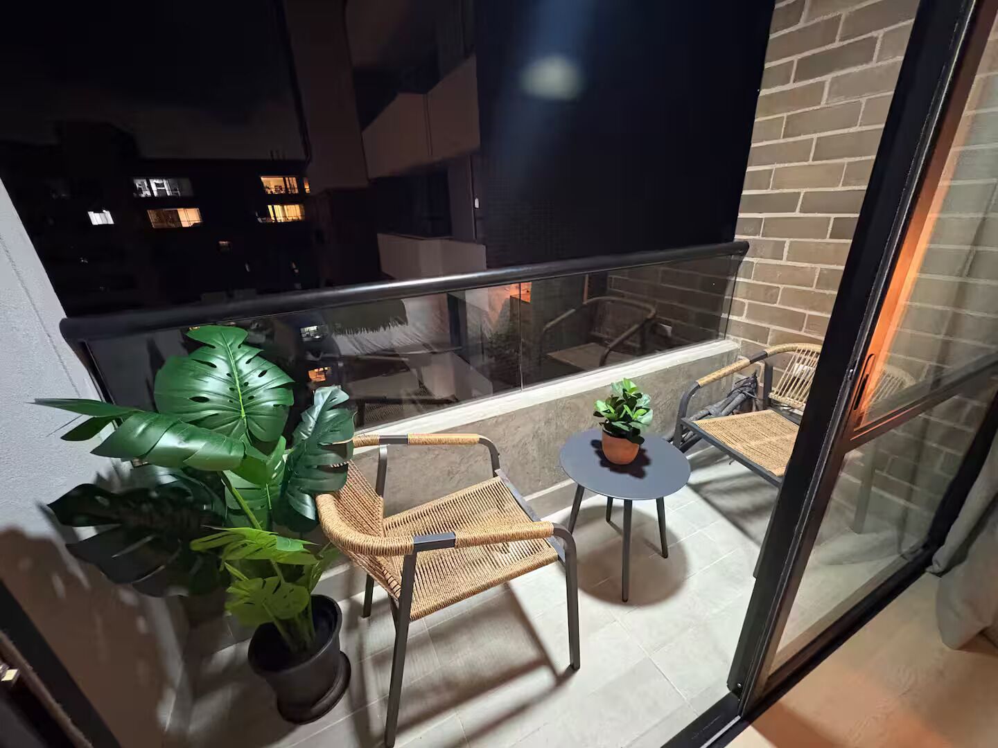 Un balcon avec des fauteuils en osier, une petite table et une plante en pot.