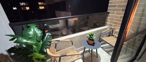 A balcony with wicker chairs, a small table, and a potted plant.