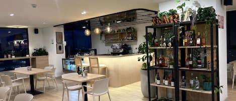 A modern restaurant with a bar area, seating, and a variety of plants.