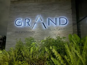 Eine Gebäudefassade mit beleuchteter Schilderung, auf der 'GRAND' und 'By LINARES' steht.