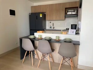 Eine moderne Küche mit einem schwarzen Kühlschrank, Holzschränken, einer Edelstahl-Spüle und Barhocker.