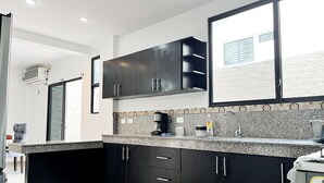 A modern kitchen with black cabinets, granite countertops, a built-in oven, and a large window. - House with Private Pool, BBQ, and Jacuzzi in Guayaquil's Social District (Milann Turin)