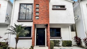A modern two-story house with a black door, a balcony, and a satellite dish. - House with Private Pool, BBQ, and Jacuzzi in Guayaquil's Social District (Milann Turin)
