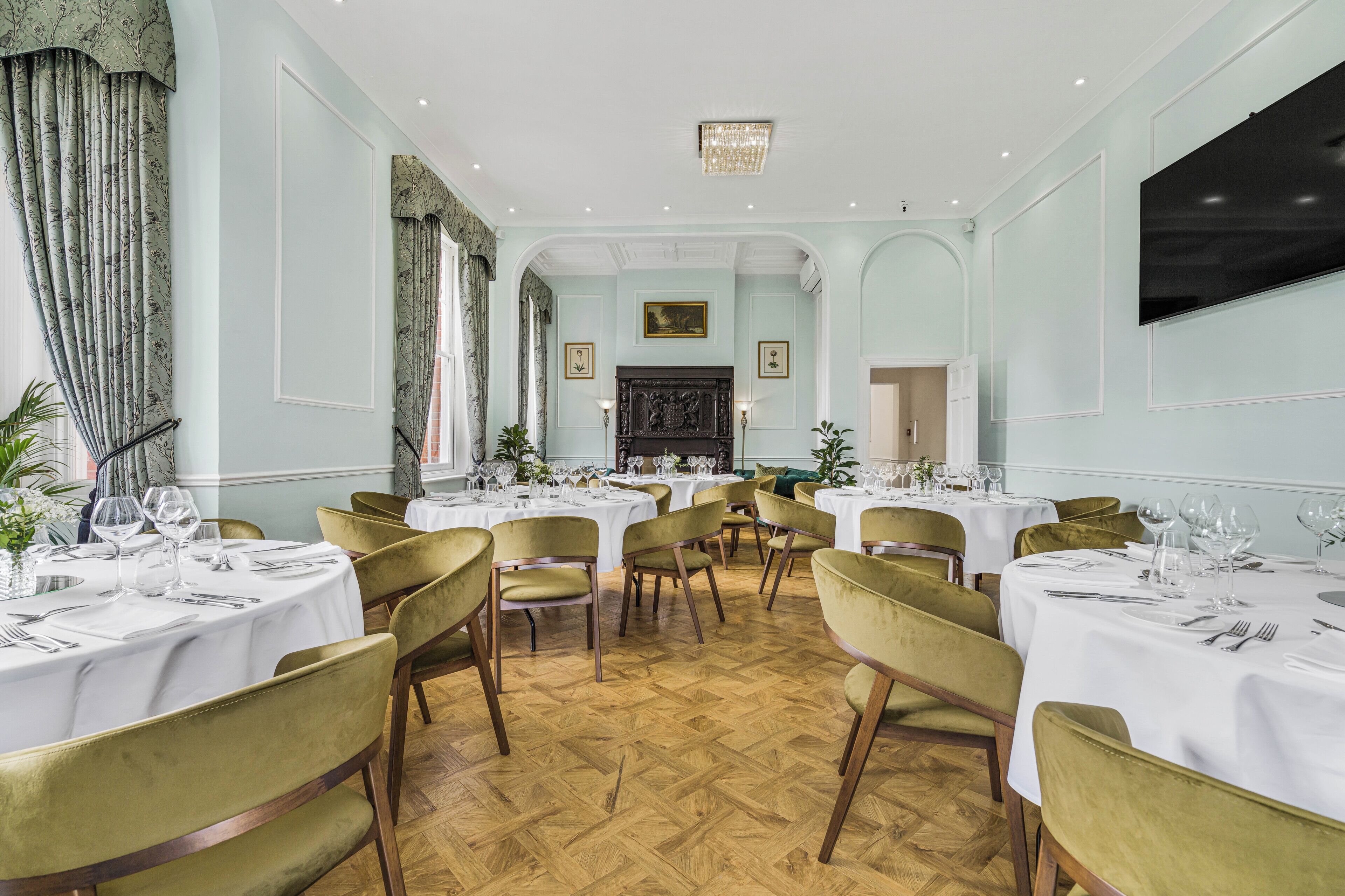 A formal dining room with multiple tables, chairs, and a fireplace.