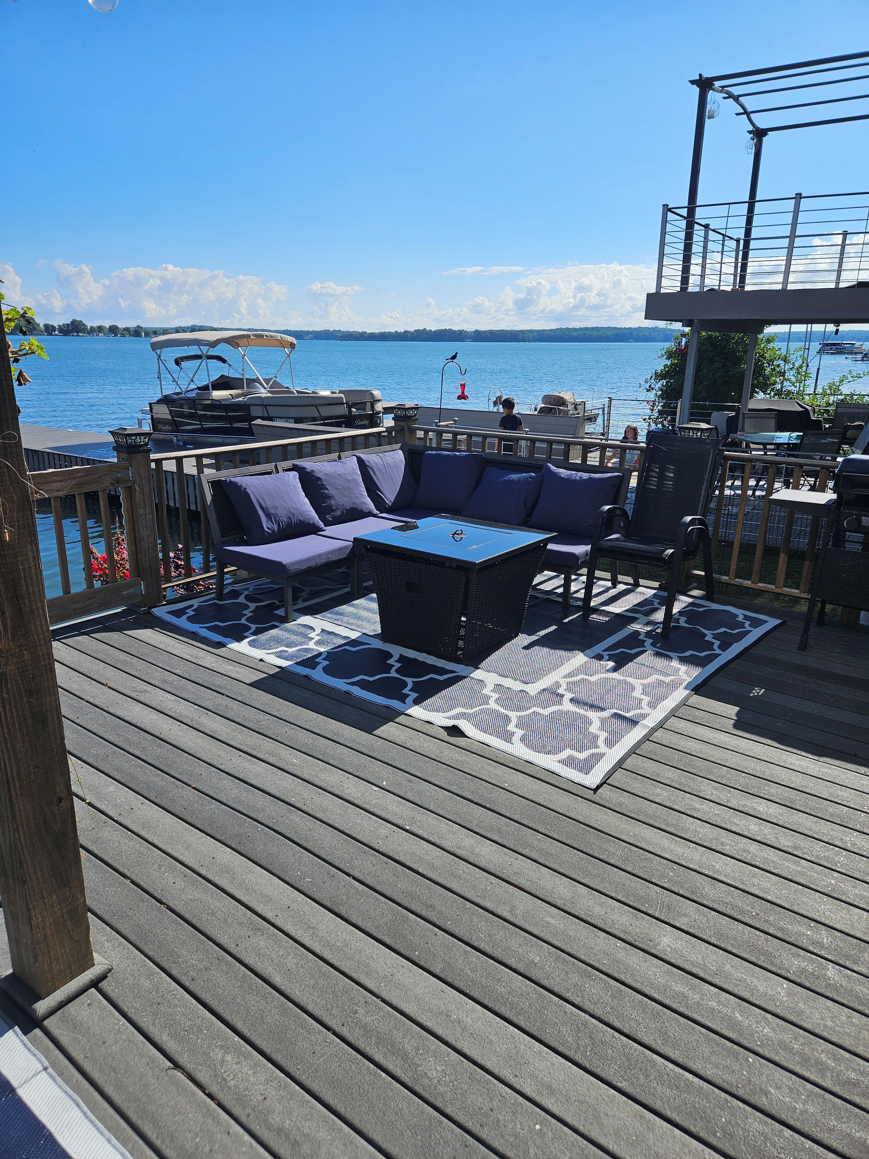 Eine Terrasse mit einer blauen Couch, einem Esstisch und Grillplatz.