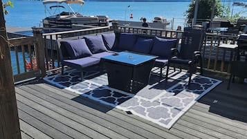 Eine Terrasse mit einer blauen Couch, einem Esstisch und Grillplatz.