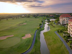 Ein Golfplatz mit Wasserspiel, einer Straße und einem Gebäude mit rotem Dach.
