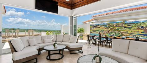 A modern living room with a sectional sofa, round coffee tables, and a large window with a view of a landscape.