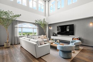 A spacious living room with a large sofa, a coffee table, and a TV mounted on the wall. - Luxury 3BR Villa Royal at Plantation (Dorado)