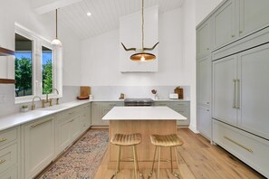 A modern kitchen with a large island, pendant lighting, and light-colored cabinetry. - Luxurious Lake-View Retreat in Historic Old Huntsville Spa, Sauna, Hot Tub, Heated Driveway (Huntsville)