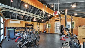 Ein Fitnessstudio mit Trainingsgeräten, einem Gewichtständer und einem Rudergerät.