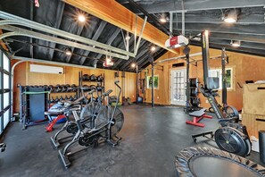 A gym with exercise equipment, a weight rack, and a rowing machine. - Luxurious Lake-View Retreat in Historic Old Huntsville Spa, Sauna, Hot Tub, Heated Driveway (Huntsville)