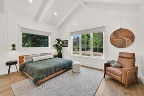 A bedroom with a bed, a chair, a window, and a plant. - Luxurious Lake-View Retreat in Historic Old Huntsville Spa, Sauna, Hot Tub, Heated Driveway (Huntsville)