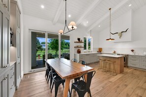 Eine moderne Küche mit Holztisch, Barhocker und Blick ins Freie.