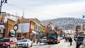 A snow-covered street with buildings, a clock, and a bus. - Spring break Ski trip at Park City!! (Park City)
