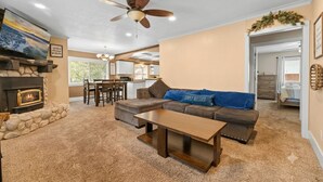 A living room with a fireplace, a sofa, a coffee table, and a ceiling fan. - Paramount Escape Big Bear-Close to Everything -Tesla Universal EV- Foos Ball (Big Bear Lake)
