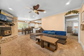 Ein Wohnzimmer mit Kamin, einer Couch, einem Couchtisch und einem Deckenventilator.