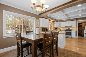 Une cuisine spacieuse avec des meubles blancs, un îlot central et un coin repas doté de chaises en bois.