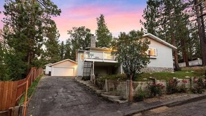A two-story house with a front porch, a garage, and a stone chimney. - Paramount Escape Big Bear-Close to Everything -Tesla Universal EV- Foos Ball (Big Bear Lake)