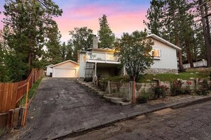 Ein zweistöckiges Haus mit Veranda, Garage und einem Steinsschornstein.