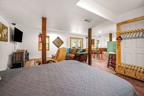 A spacious room with a large bed, a sofa, a dining area, and a wooden door.