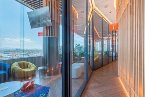 A modern interior with a curved glass wall, a mounted television, and a view of the cityscape. - Central loft with luxury amenities, close to the historic center and El Ángel (Ciudad de México)