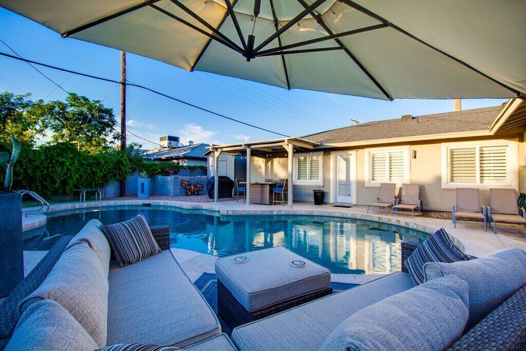 A pool area with a covered seating area, lounge chairs, and a patio.
