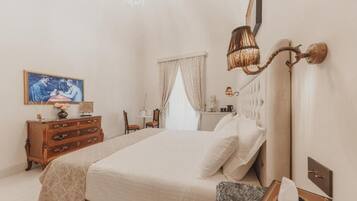 A bedroom with a bed, dresser, lamp, and artwork on the wall.