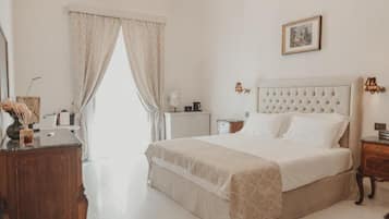 A bedroom with a large bed, a dresser, a nightstand, a lamp, and a picture on the wall.