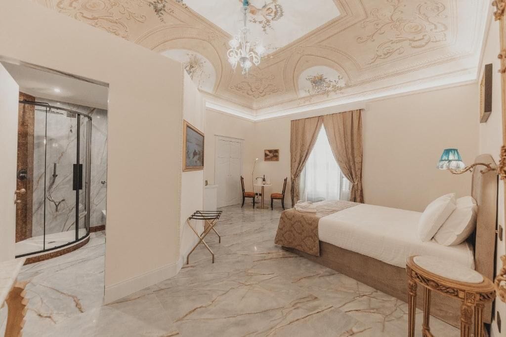 A hotel room with a bed, a shower, a chair, and a table.