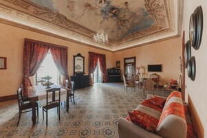Una habitación con una mesa de comedor, sillas, un sofá, un piano y una araña.
