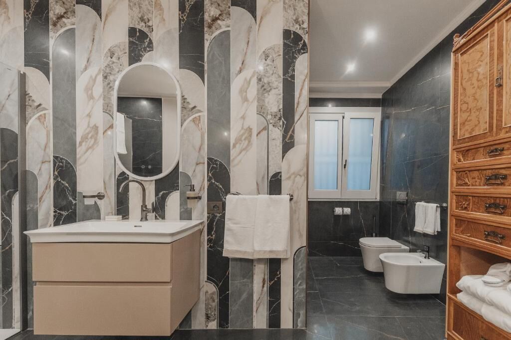 A modern bathroom with a marble vanity, a freestanding bathtub, and a wooden cabinet.