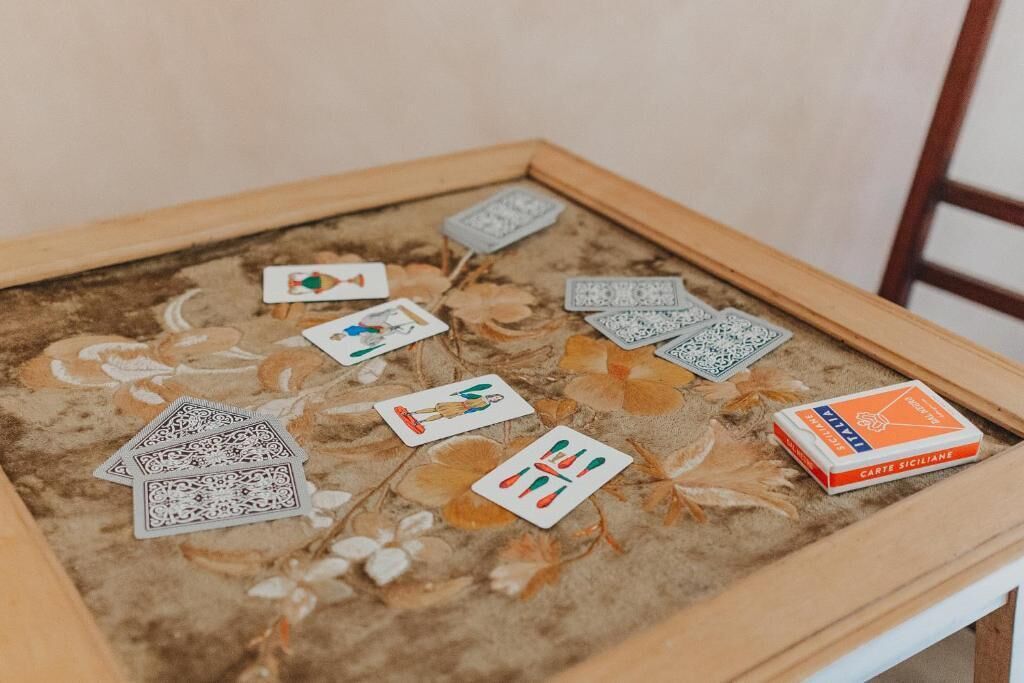 Une table décorative, ornée d’un cadre, sur laquelle on trouve un jeu de cartes et une boîte de pain sicilien.